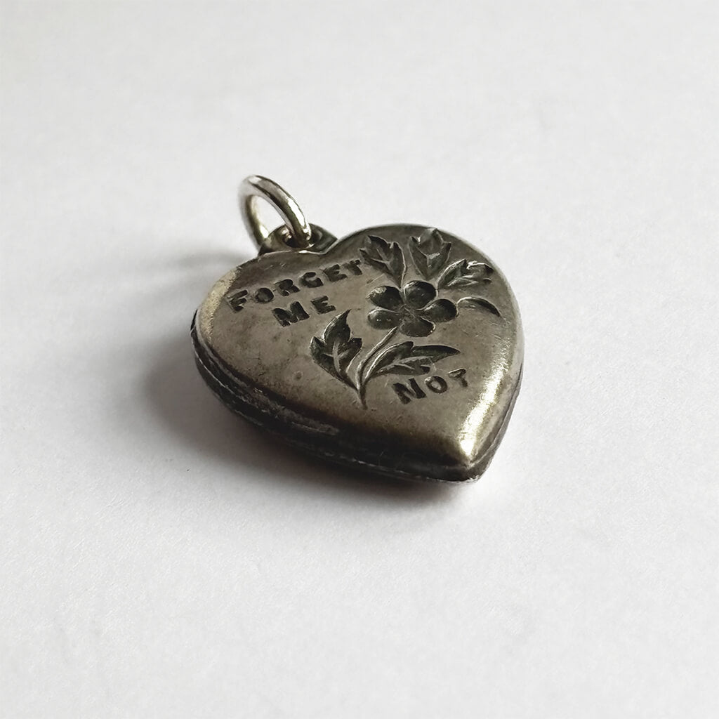 Silver heart-shaped pendant with 'Forget Me Not' engraving on a white background