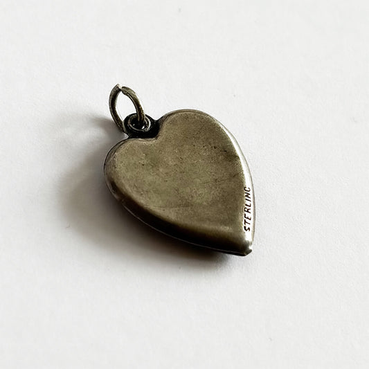 back of heart-shaped silver charm on a white background