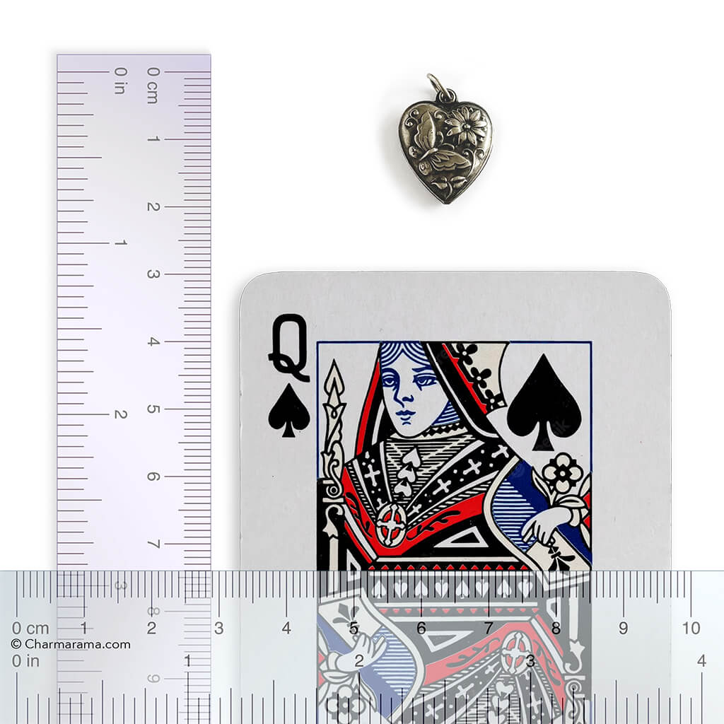 Heart-shaped pendant next to a playing card with a ruler for scale