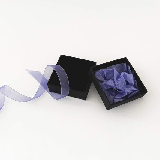 Black jewelry box with purple fabric and ribbon on a white background