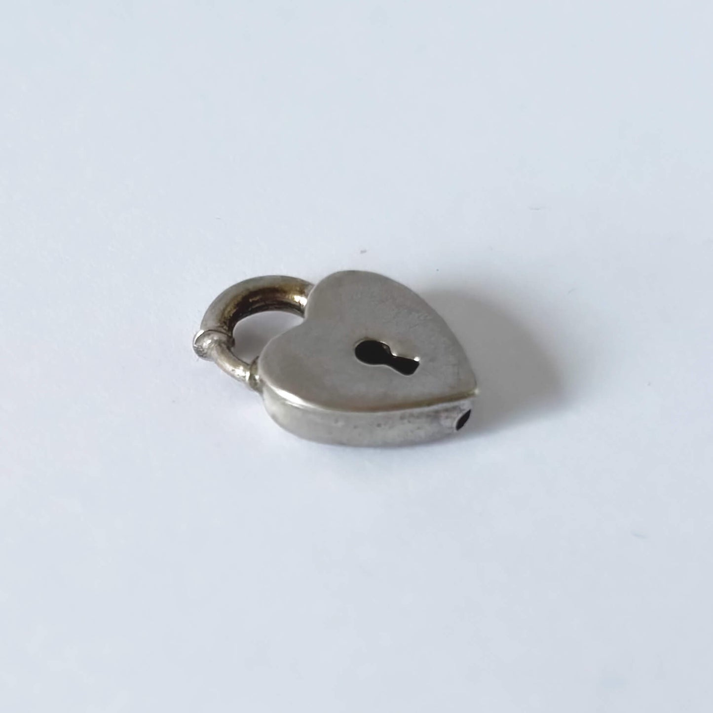 Heart-shaped silver charm bracelet clasp on a white background