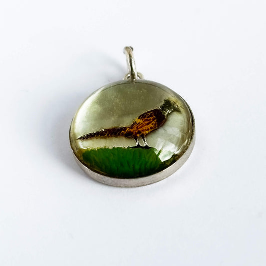 A vintage sterling silver reverse crystal pheasant charm on a white background.