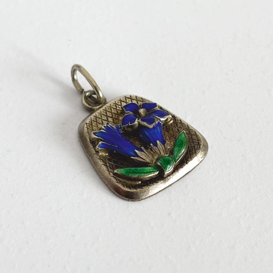Silver pendant with blue and green floral design on a white background
