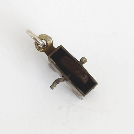 Vintage silver grindstone charm seen from above on a white background