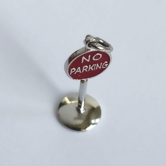 A vintage sterling silver no parking sign charm on a white background.