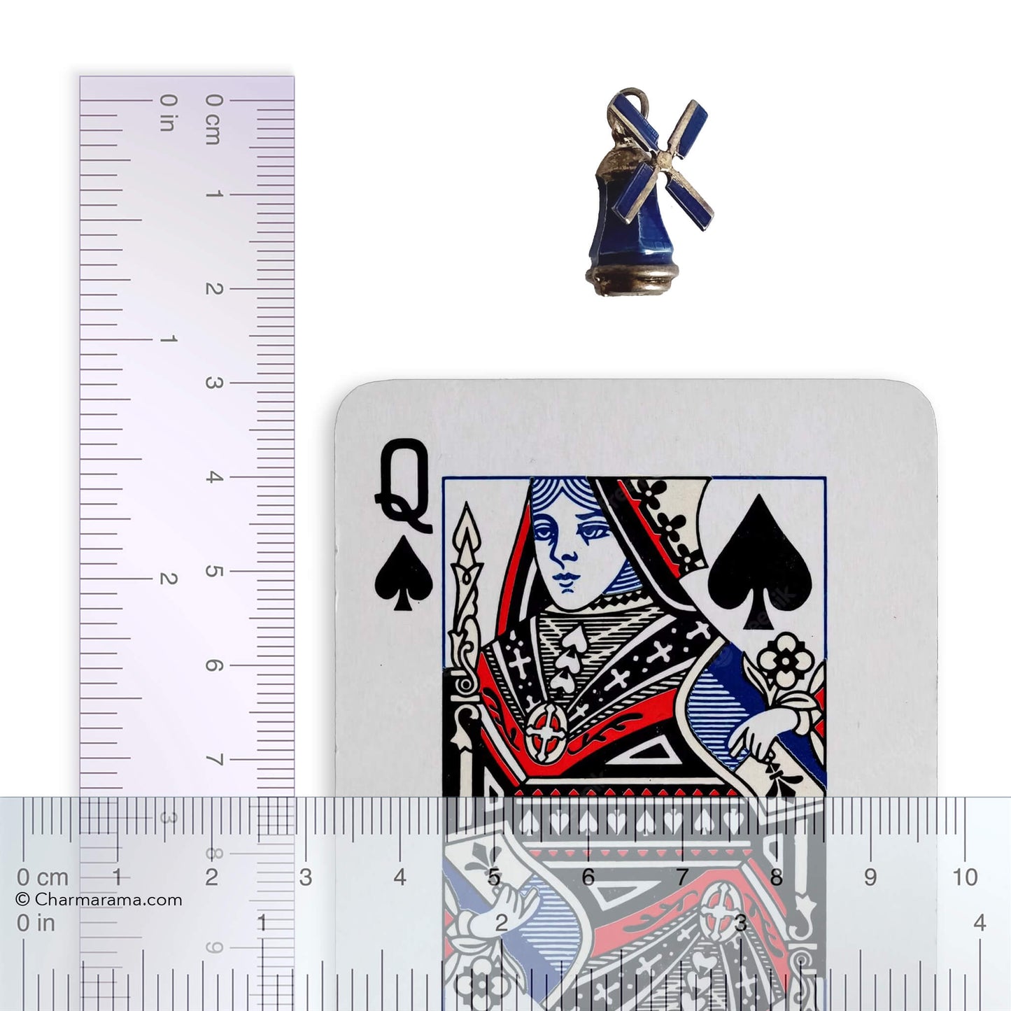 Vintage silver and blue enamel windmill charm with playing card and ruler for scale on a white background