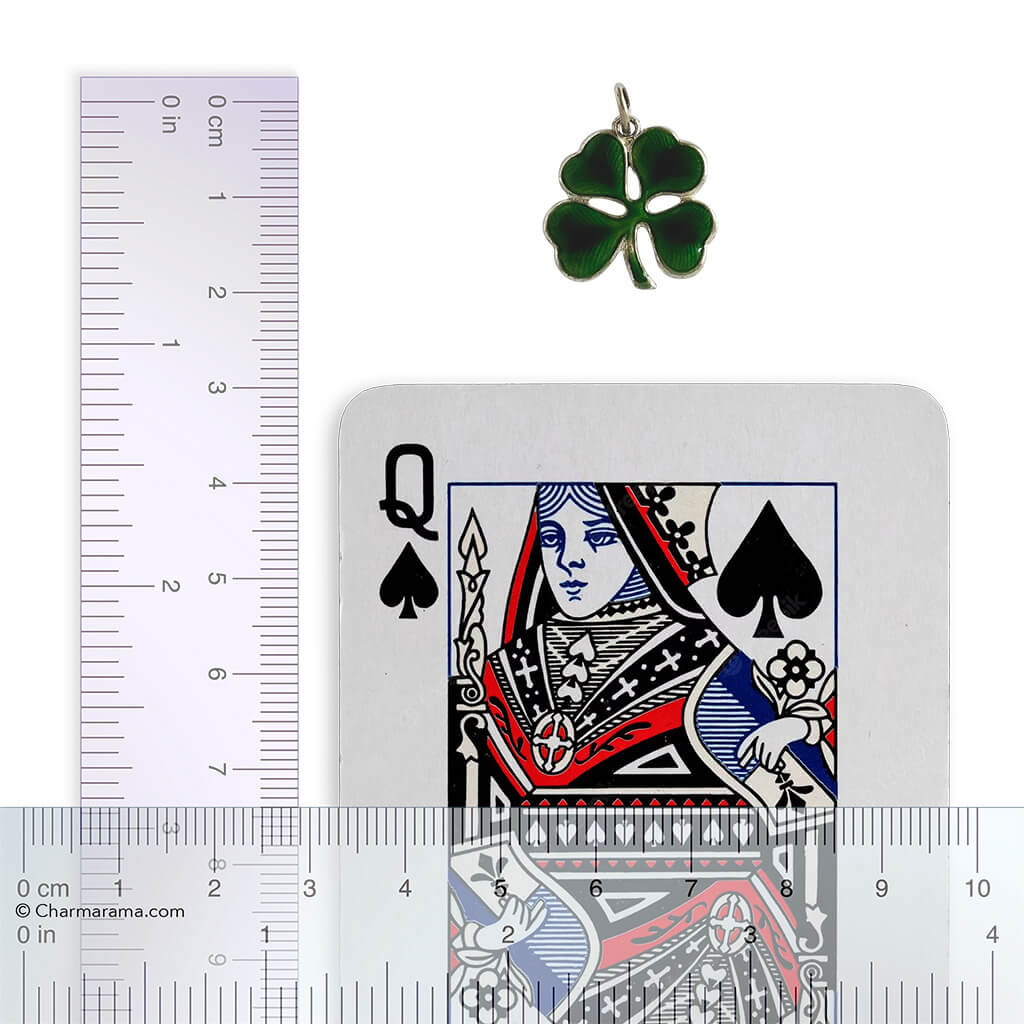 Four leaf clover charm next to a playing card with a ruler for scale