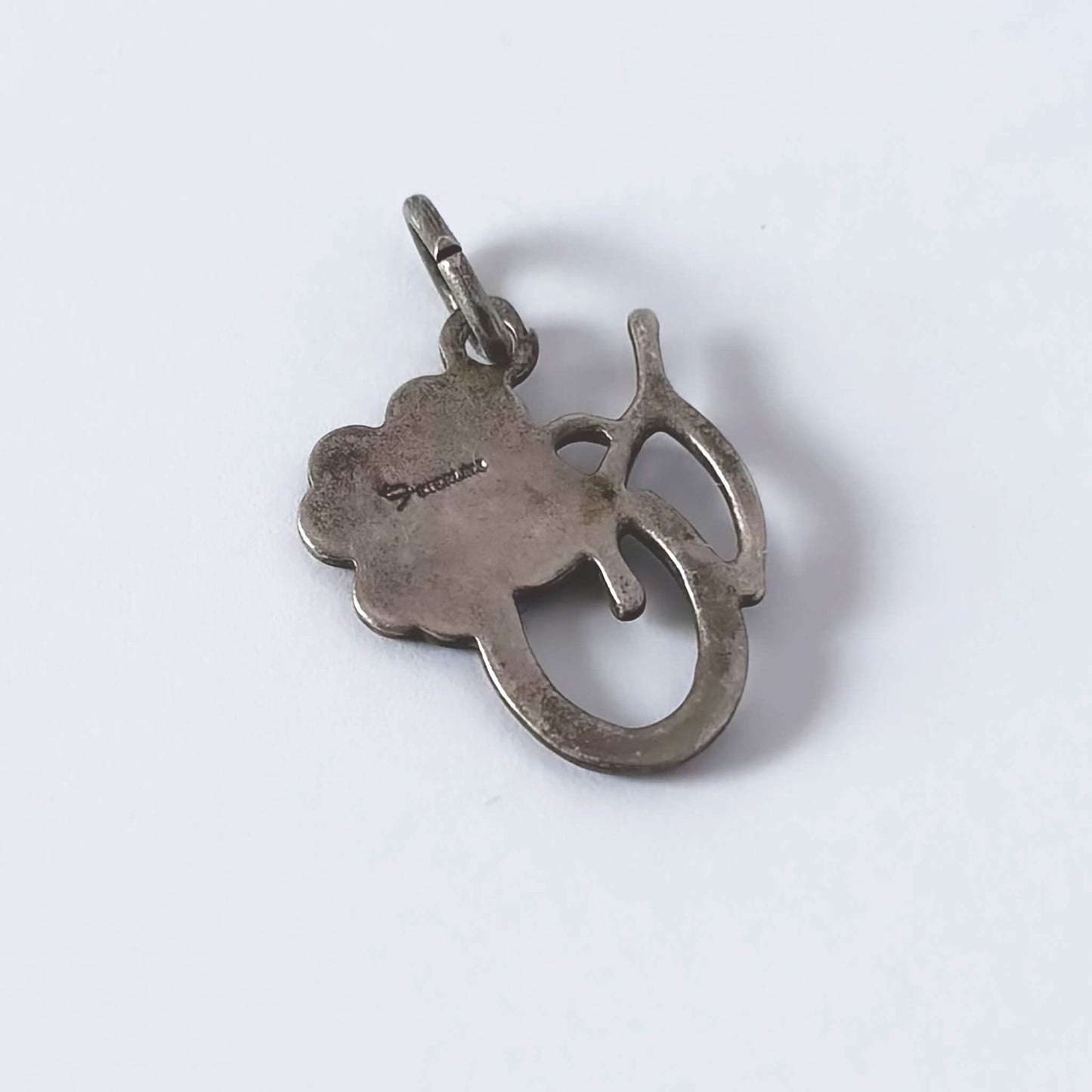 Silver pendant with a clover leaf design on a white background