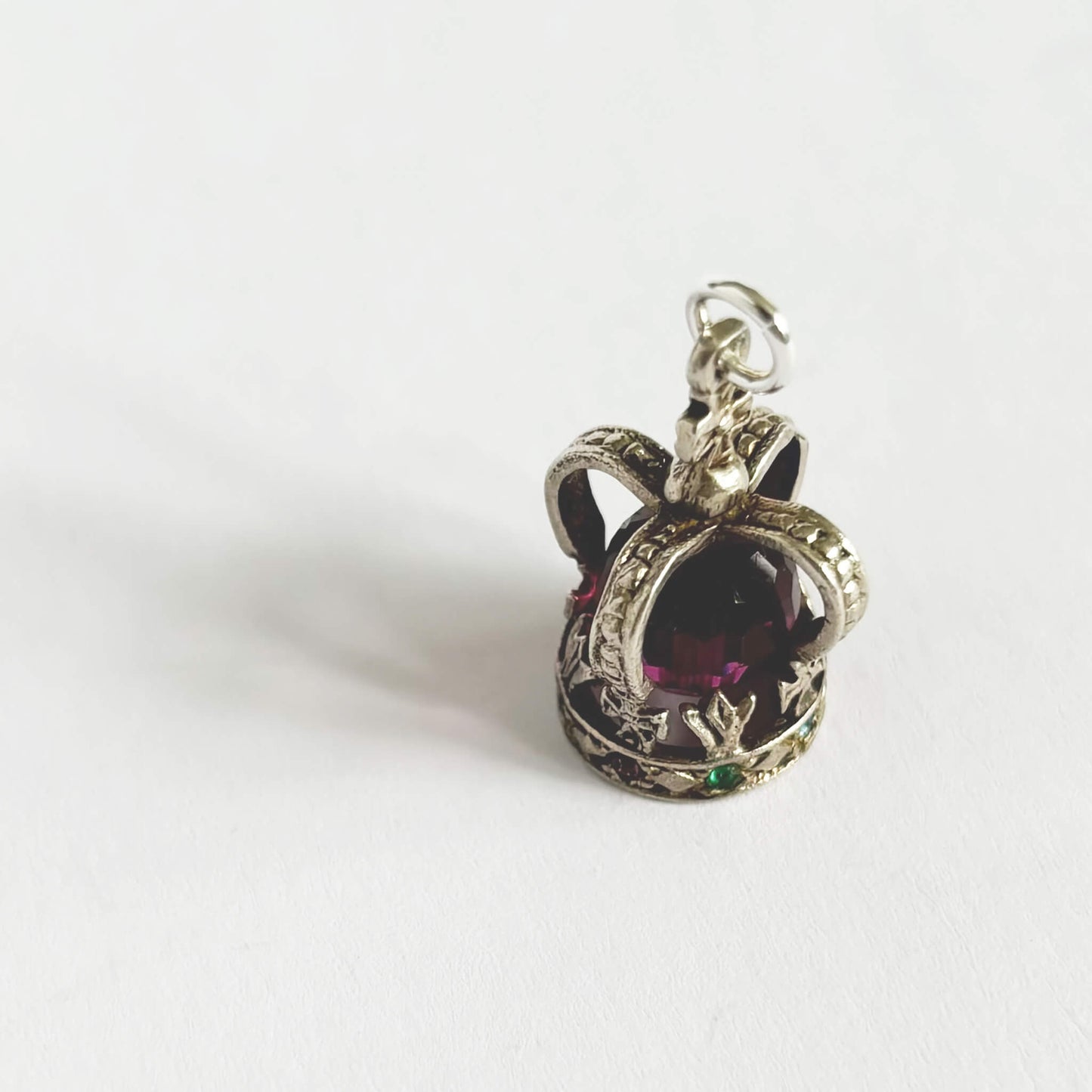 Silver crown pendant with a pink gemstone on a white background