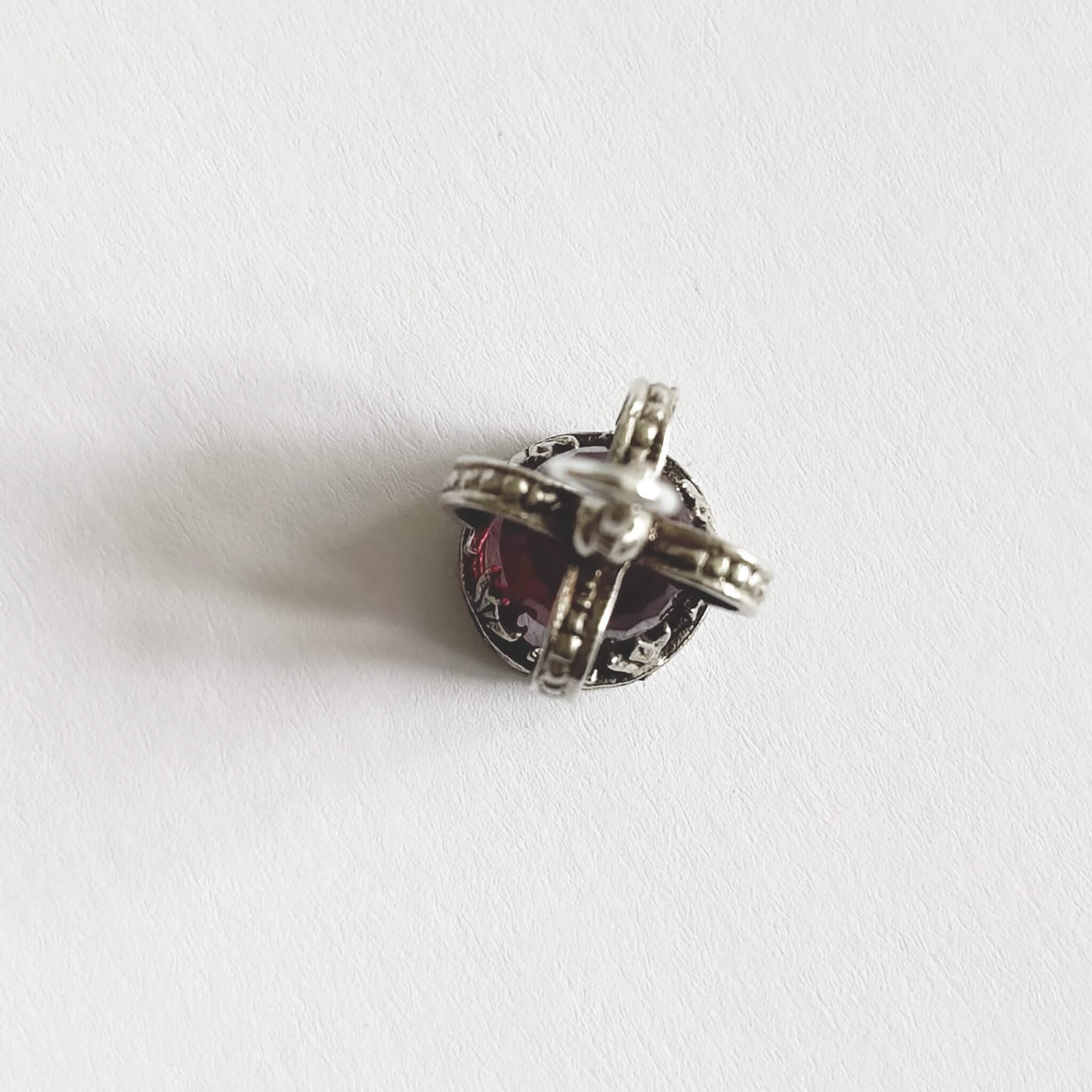 Silver crown pendant with a pink gemstone on a white background