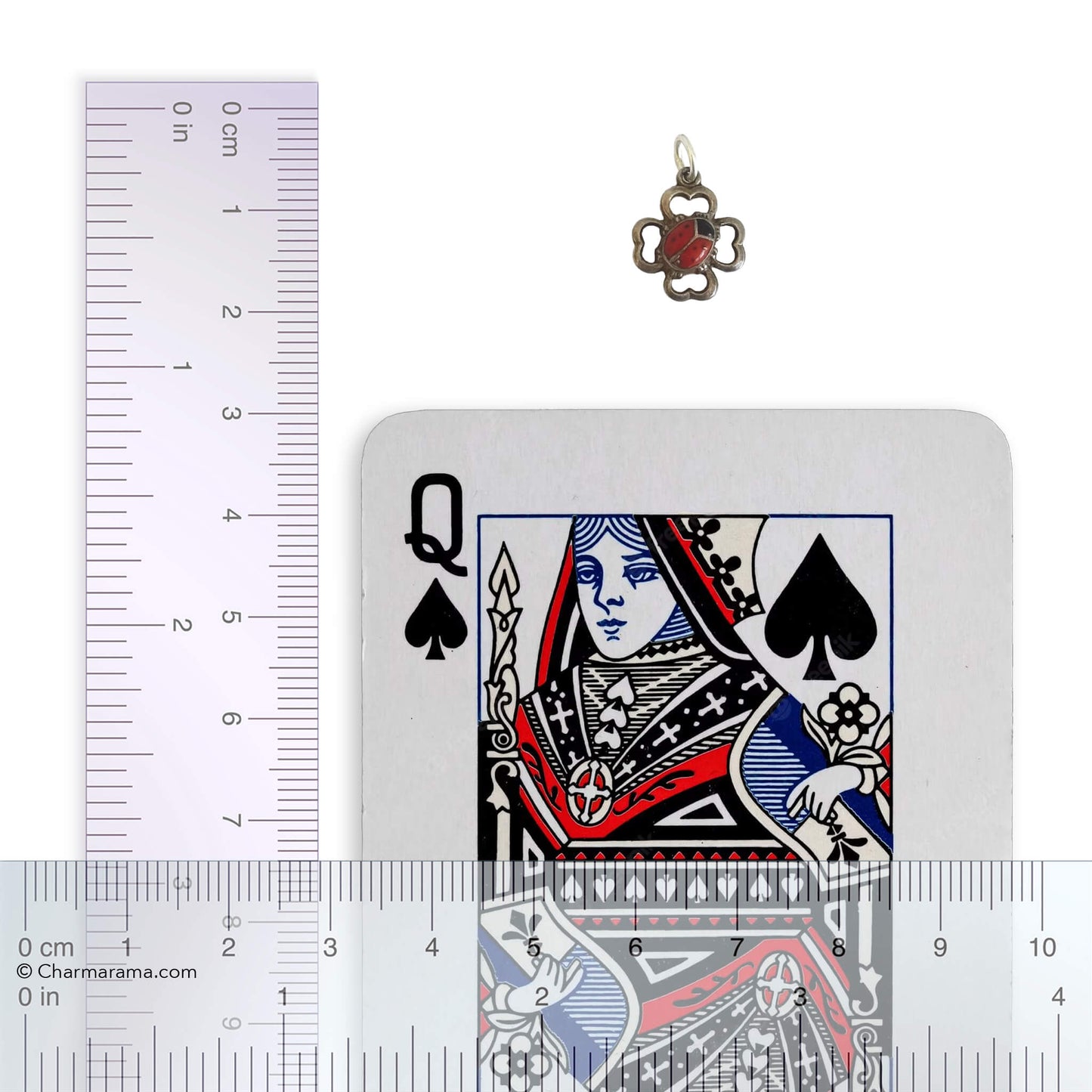 Pendant next to a playing card with a ruler for scale