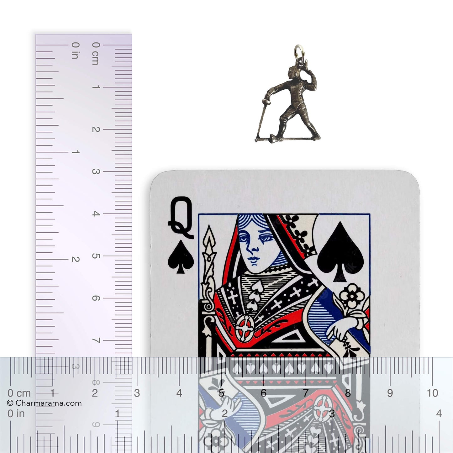 Vintage silver charm of a fencer holding a sword next to a ruler and playing card for scale on white background