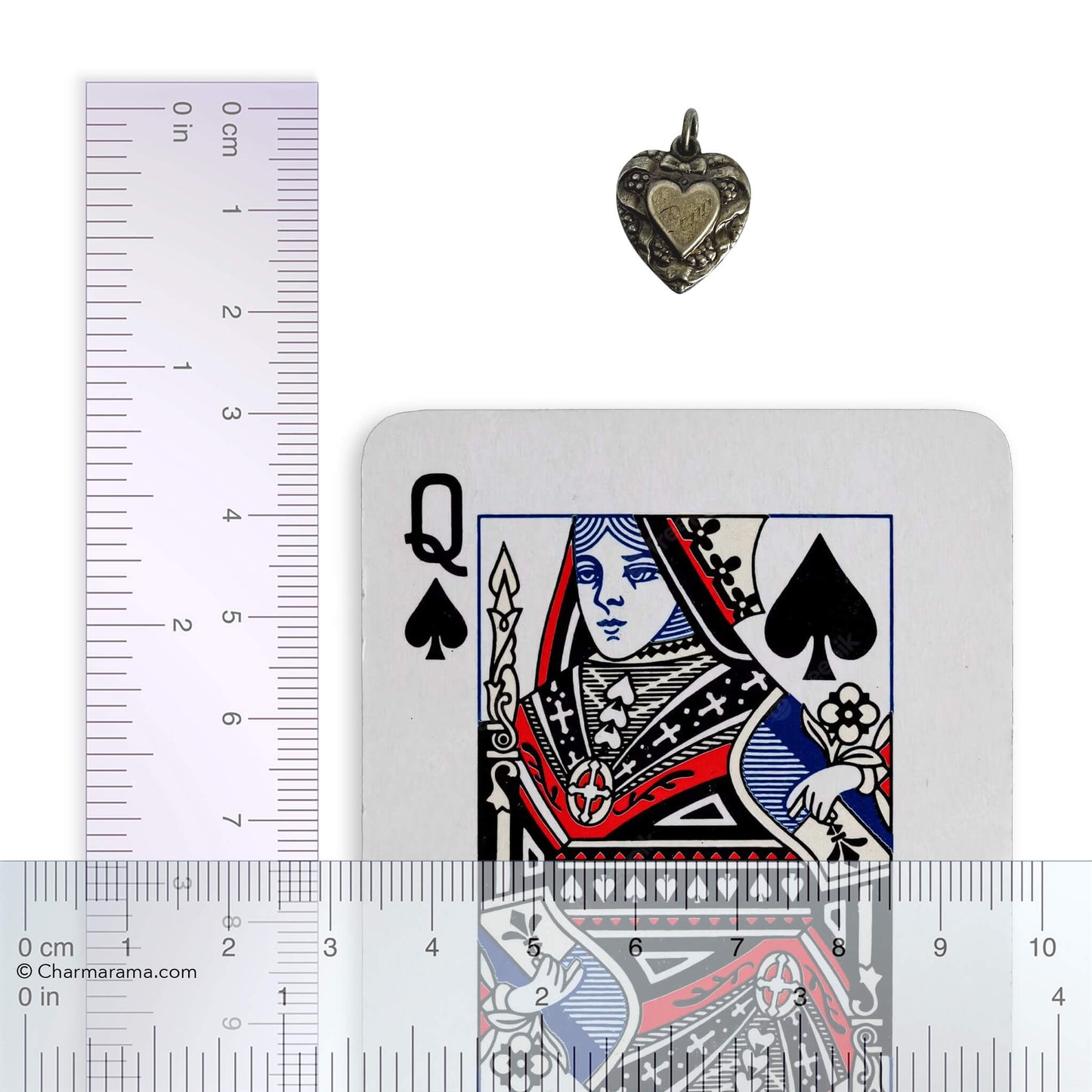 Heart-shaped pendant with playing card and ruler for scale on a white background