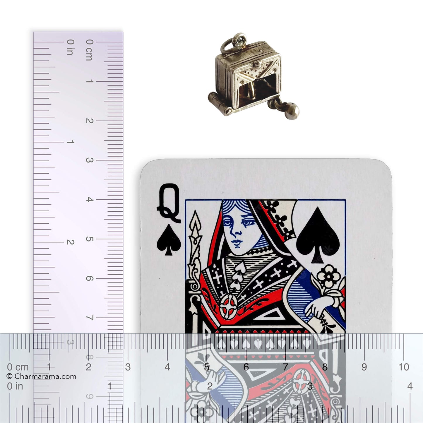 A rare vintage silver bowling alley charm by Nuvo, with playing card and ruler for scale, on a white background