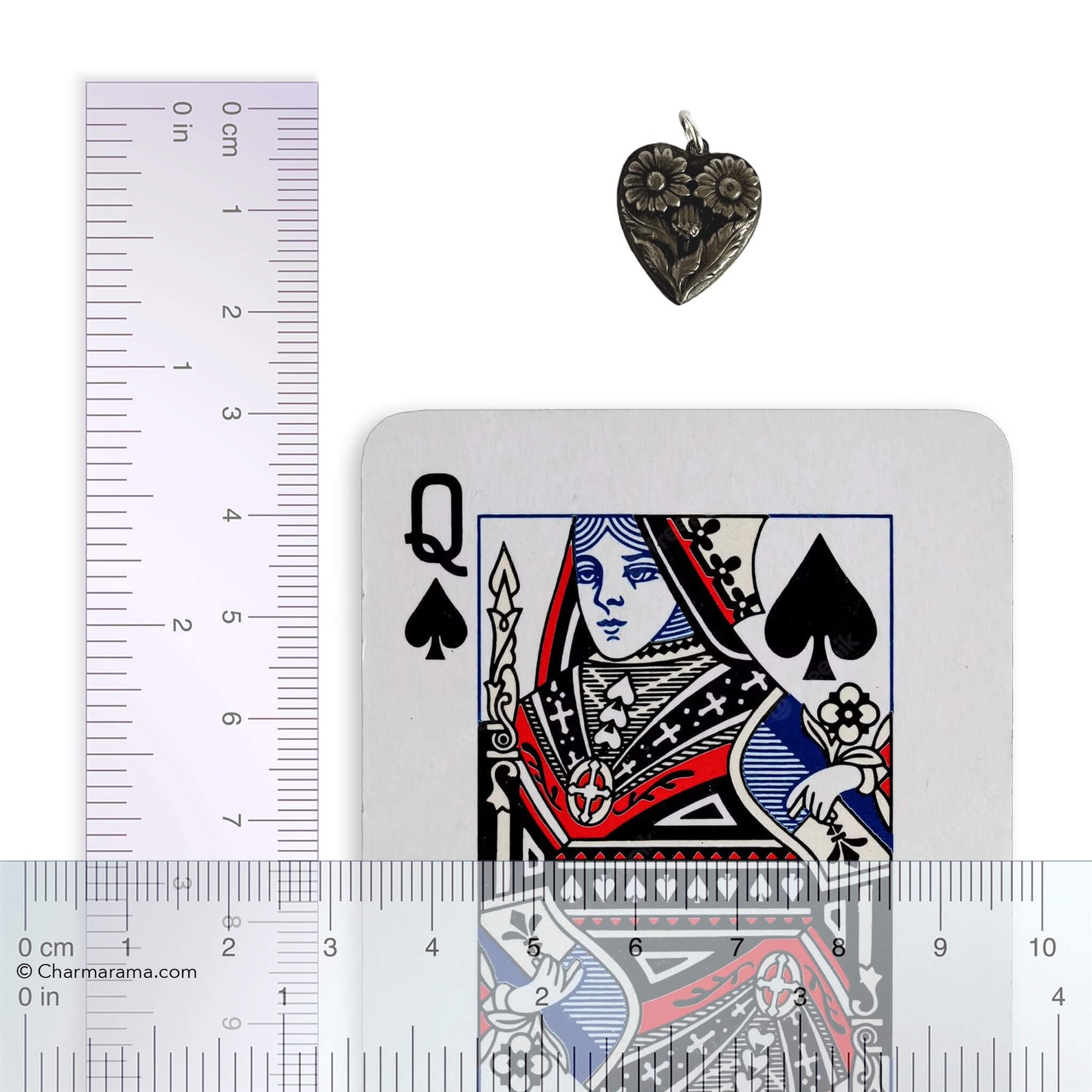 Heart-shaped pendant with a playing card and a ruler for scale on a white background