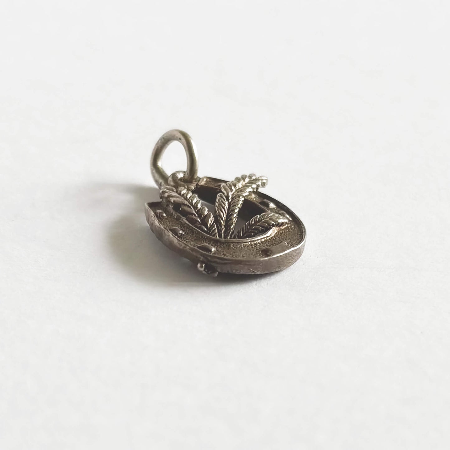 Silver pendant with leaf design on a white background