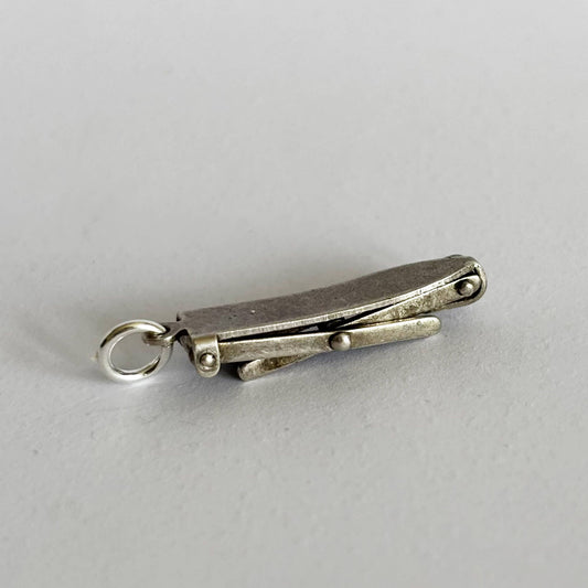 Silver ironing board charm on a light gray background