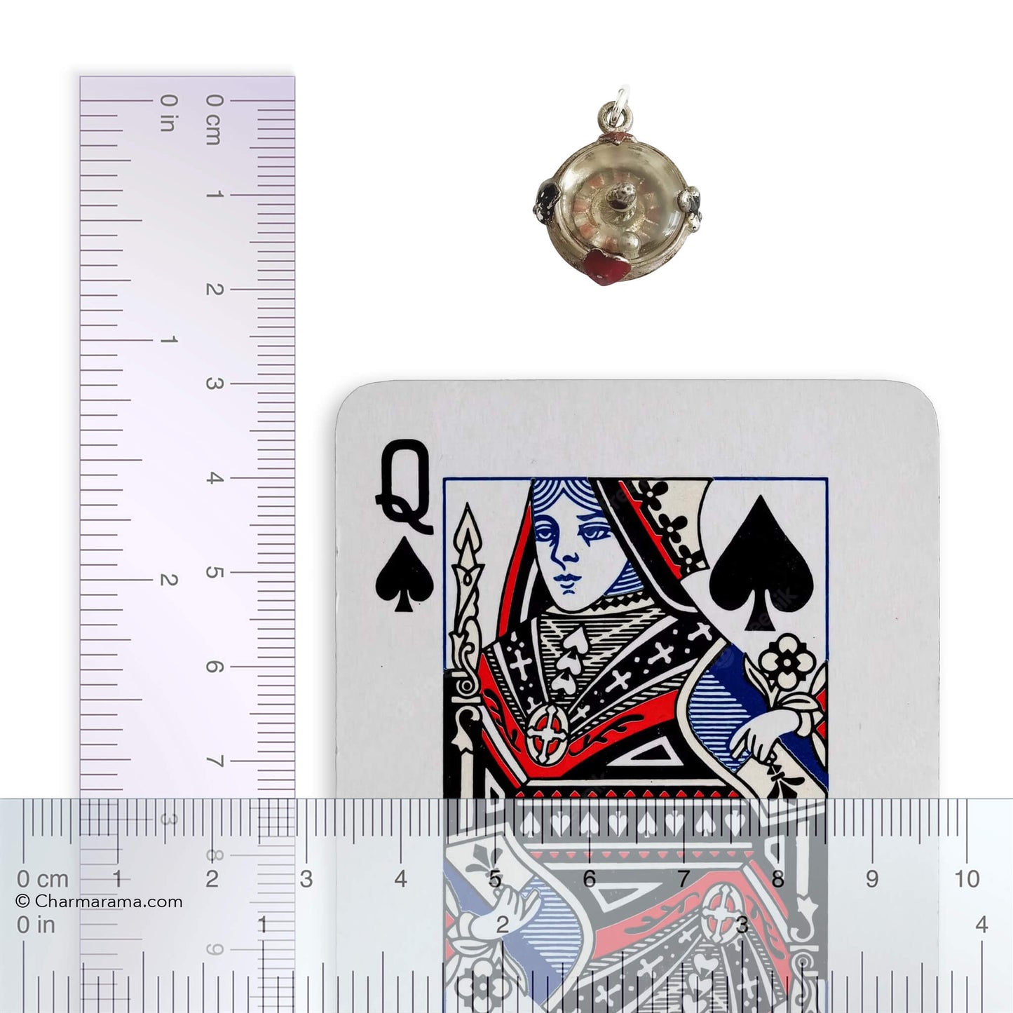 Silver roulette wheel charm next to a playing card with a ruler for scale