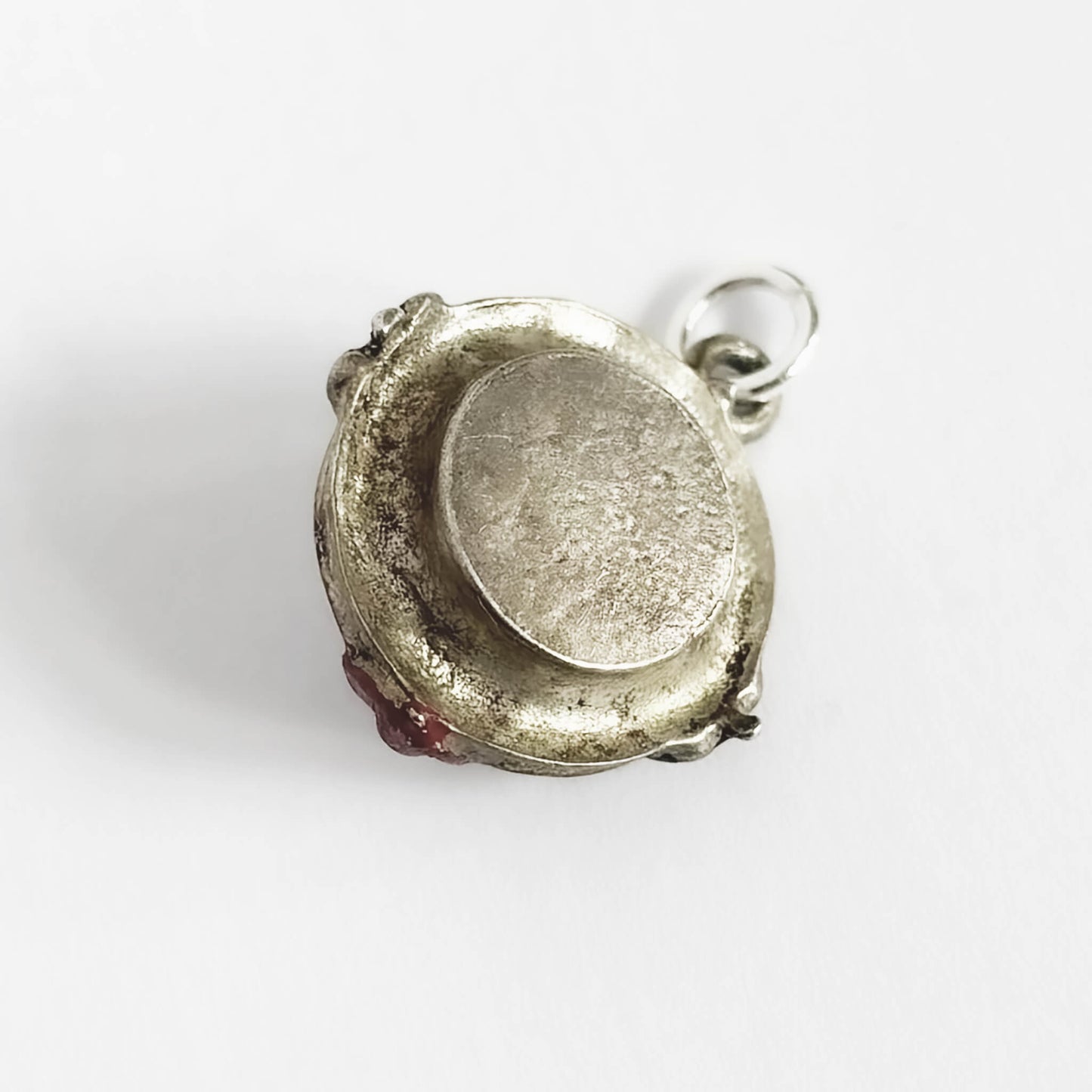 Back of a Silver roulette wheel charm pendant with red and black enamel on a white background
