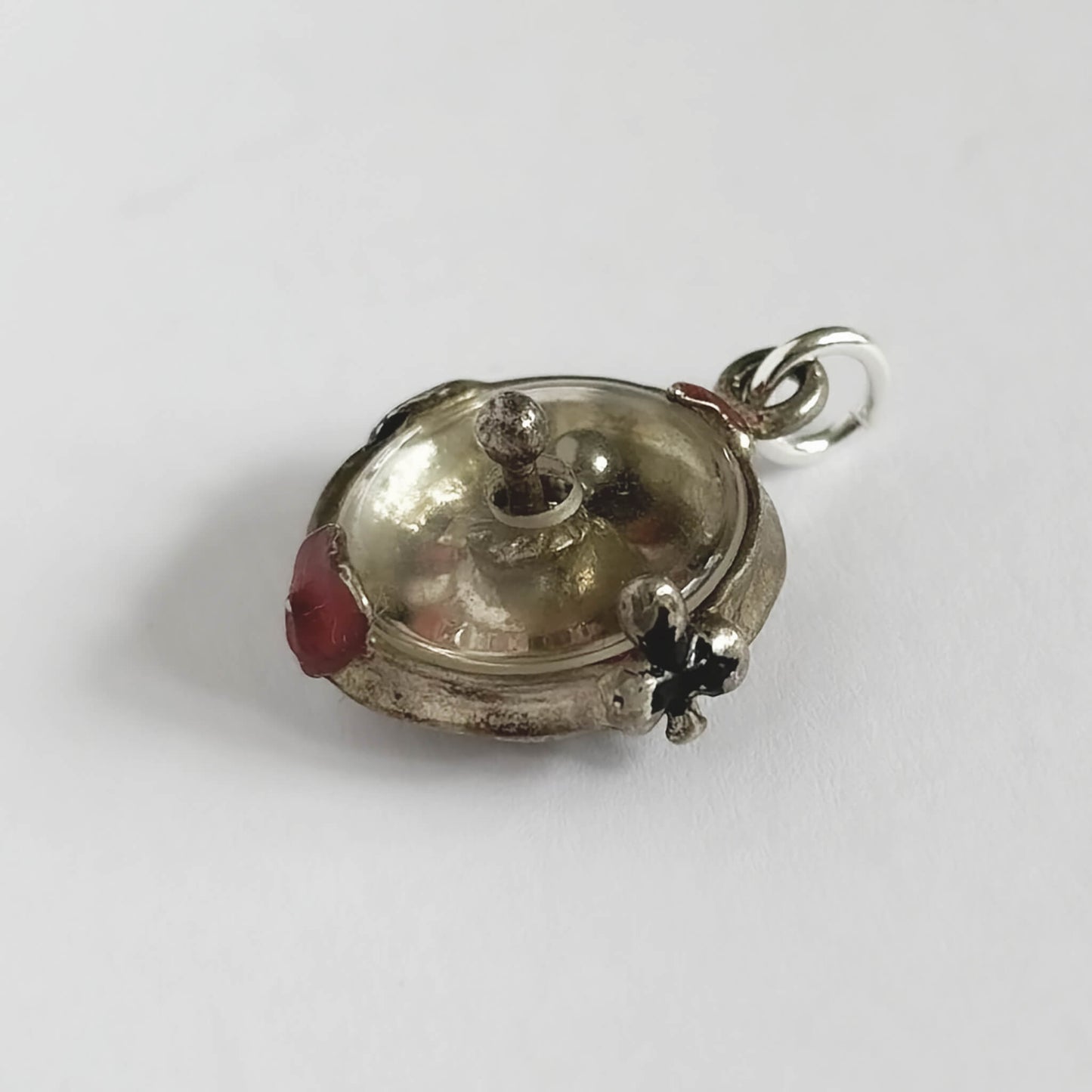 Silver roulette wheel charm pendant with red and black enamel on a white background