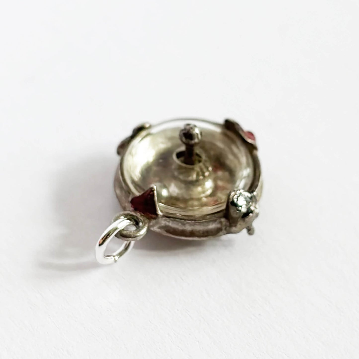 Silver roulette wheel charm pendant with red and black enamel on a white background