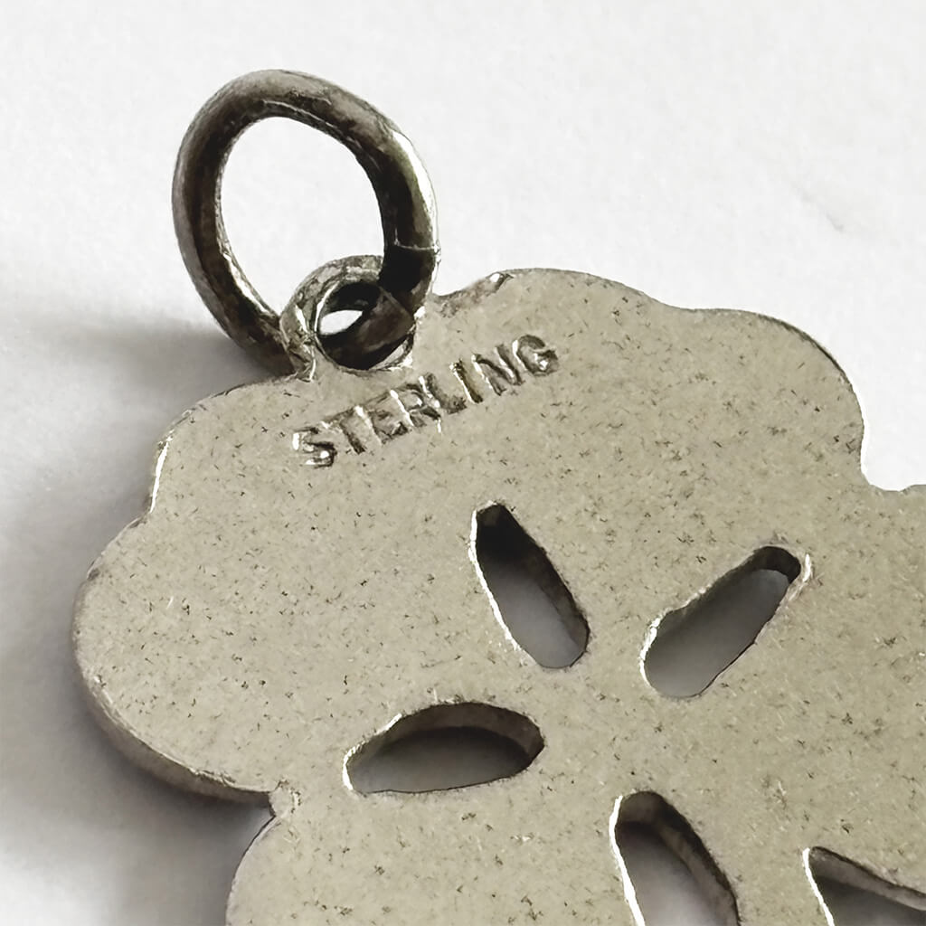 Silver pendant with 'STERLING' engraving on a white background