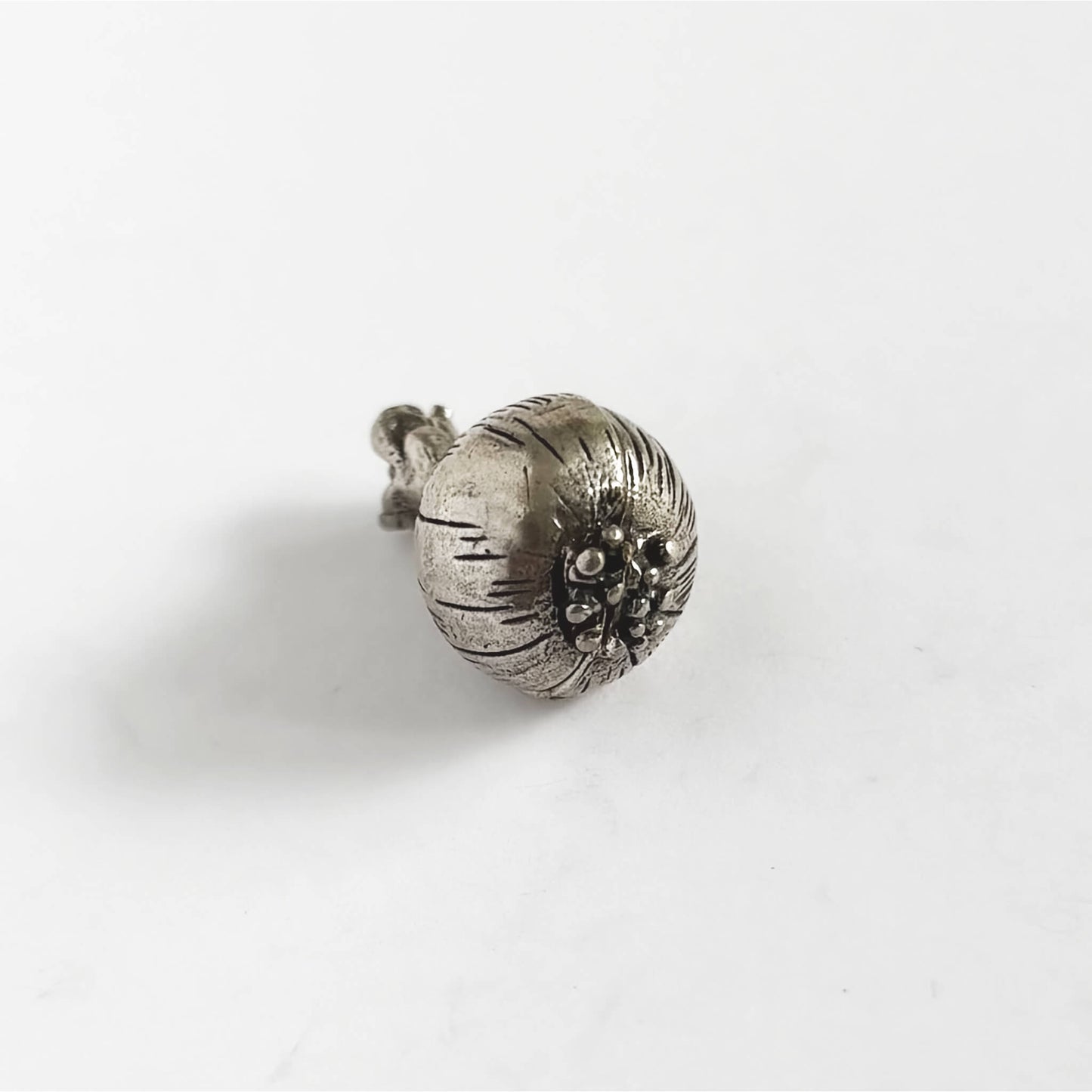 Silver onion charm on a white background