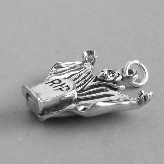 silver dracula charm seen from side on grey background