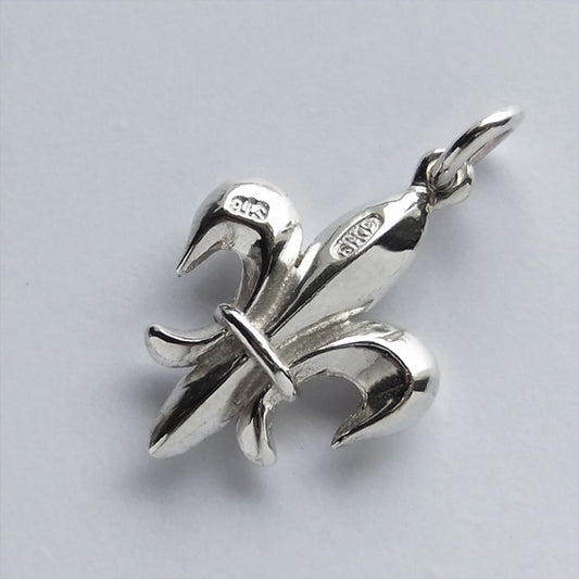 Back of a sterling silver Fleur de lis charm on a white background