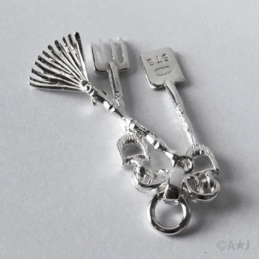 Sterling silver Garden Tools charm on a grey background