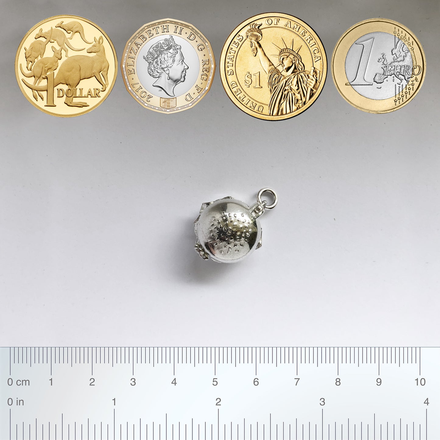 Sterling silver hamburger charm with coins and ruler on a grey background