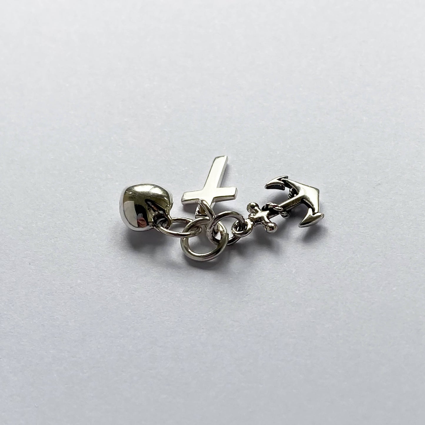 silver faith hope charity charm on grey background