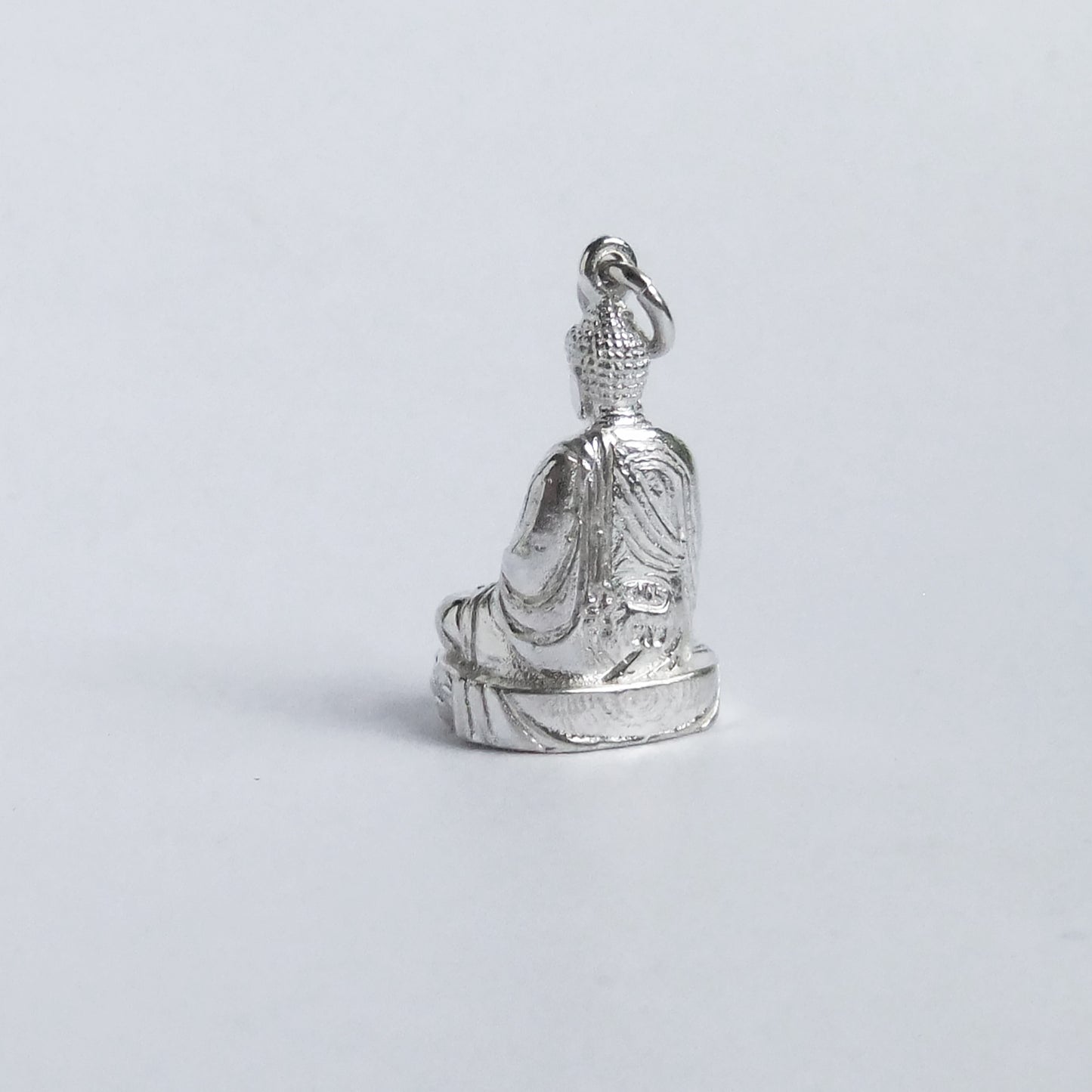 silver buddha charm from back on light grey background