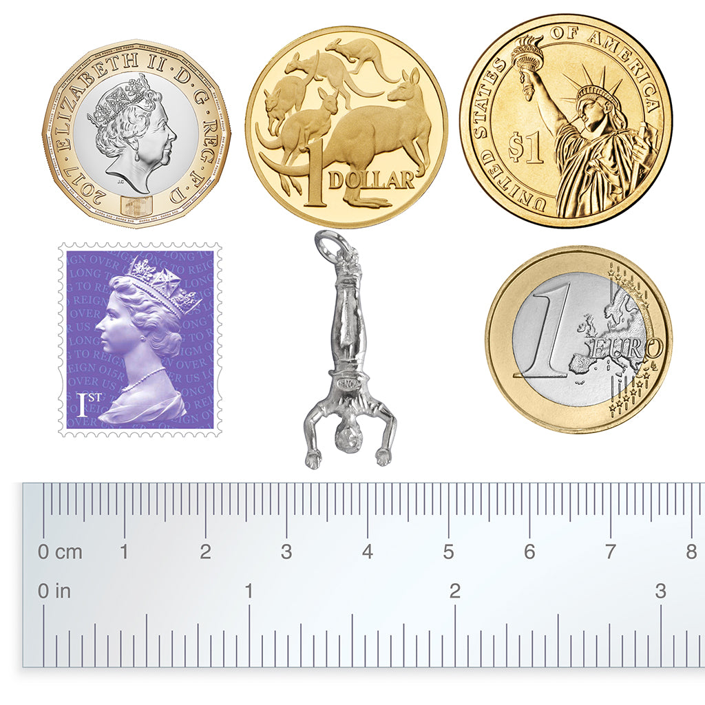 bungee jumper charm with coins stamp and ruler for scale on a white background