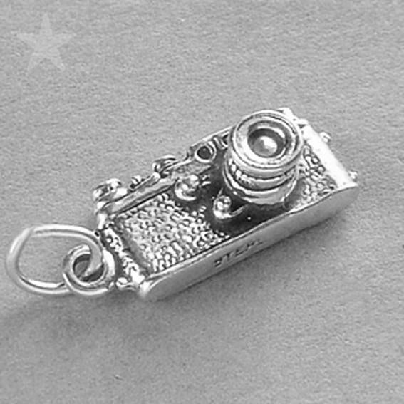 silver traditional camera charm on a grey background
