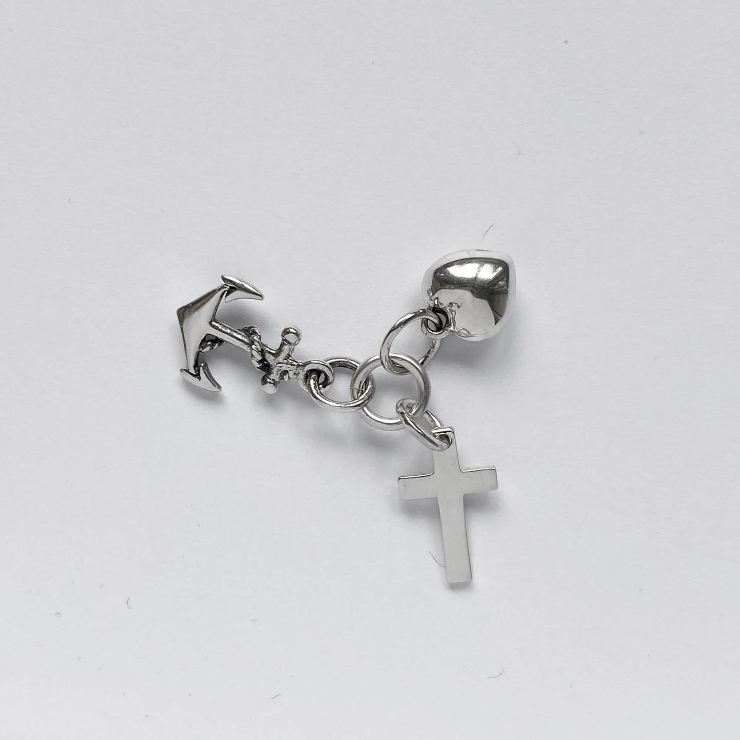 silver faith hope charity charm on light grey background