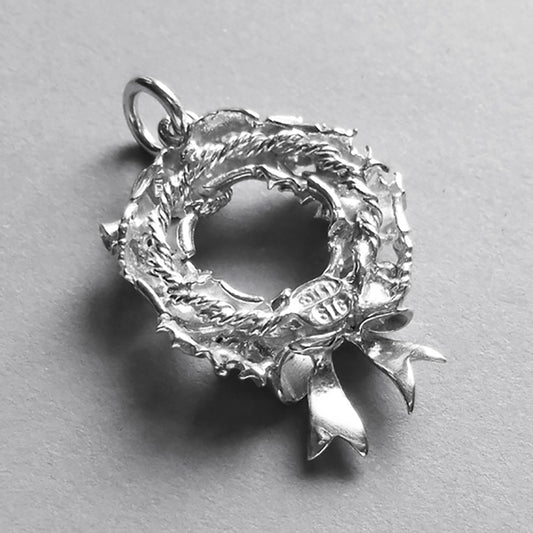 silver Christmas wreath charm seen from back on a light grey background