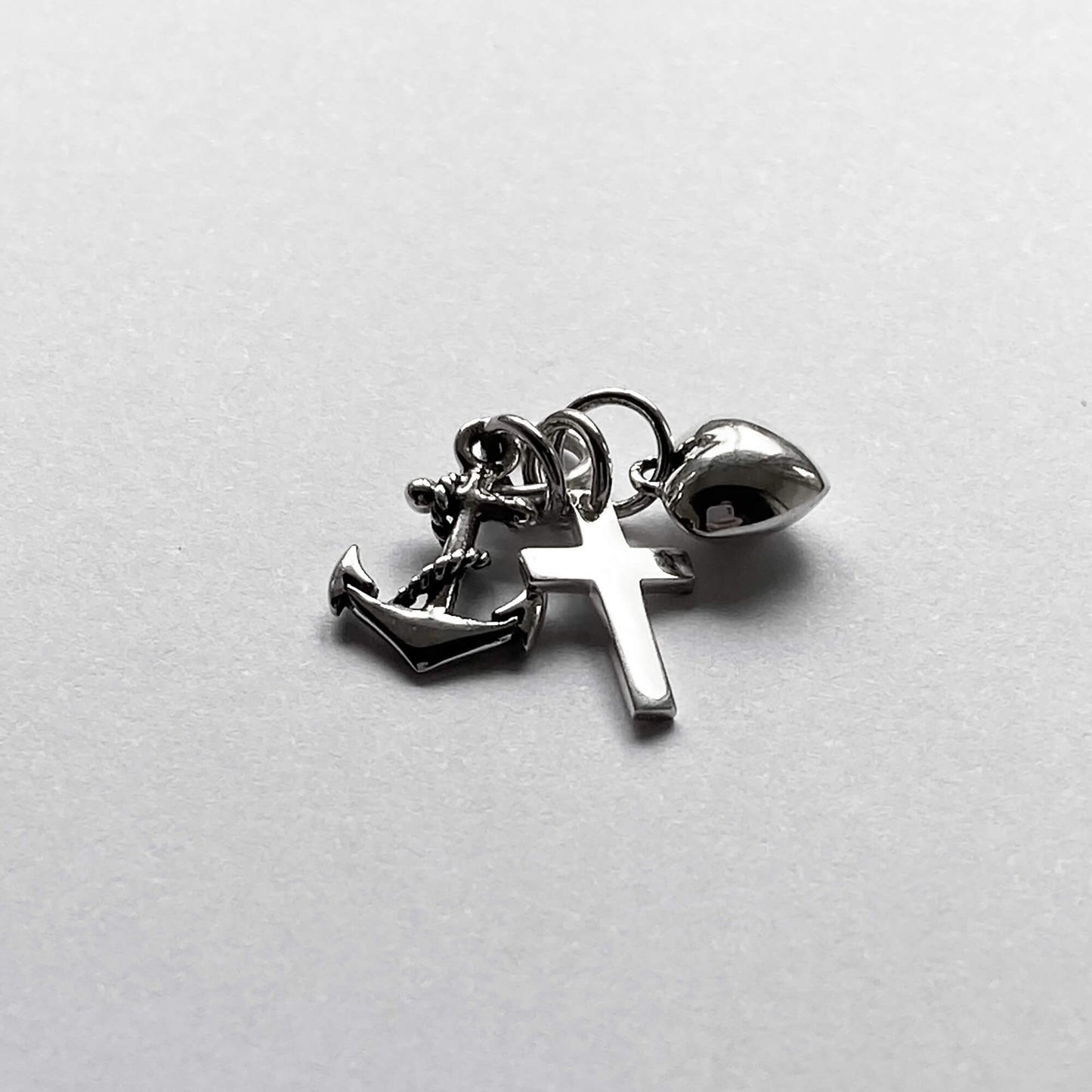 silver faith hope charity charm on light grey background