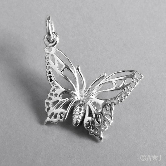 A silver filigree butterfly charm on a grey background.