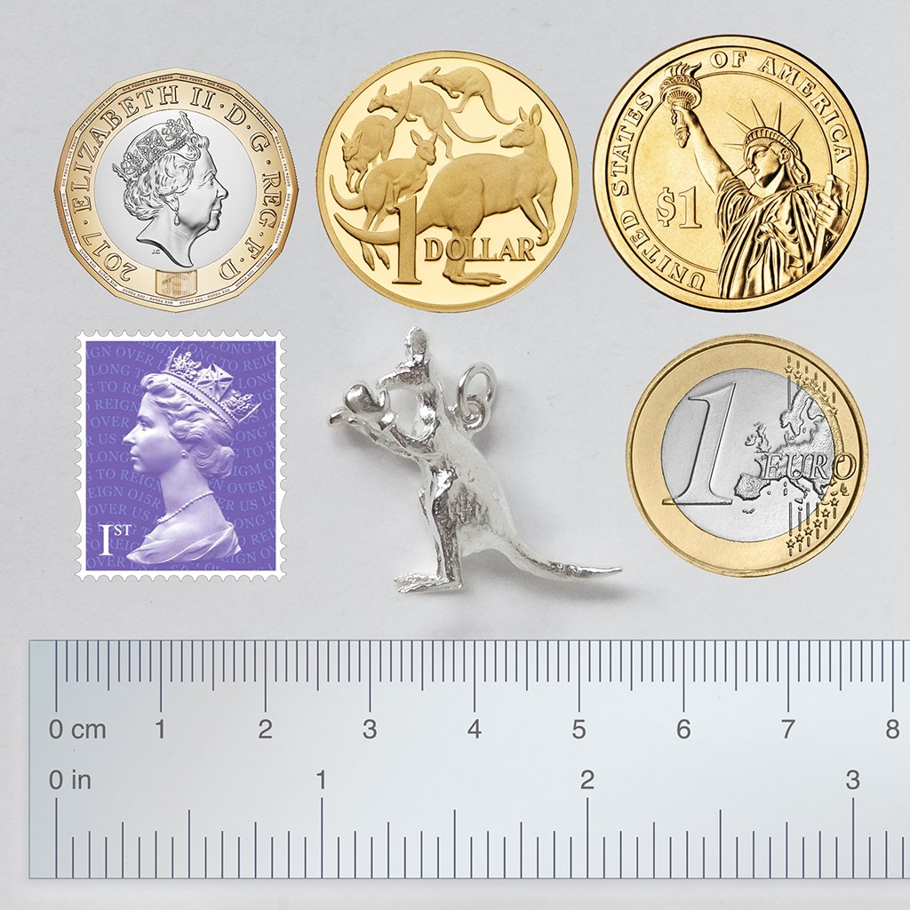 A silver boxing kangaroo on grey background with coins stamp and ruler for scale