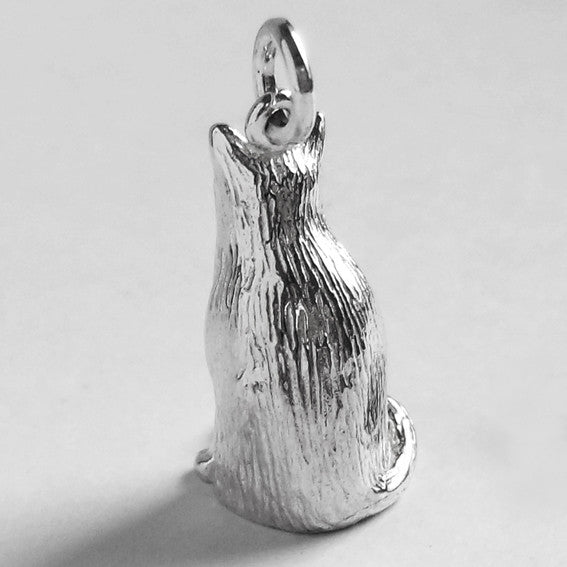 A sitting silver Birman cat charm on a grey background.