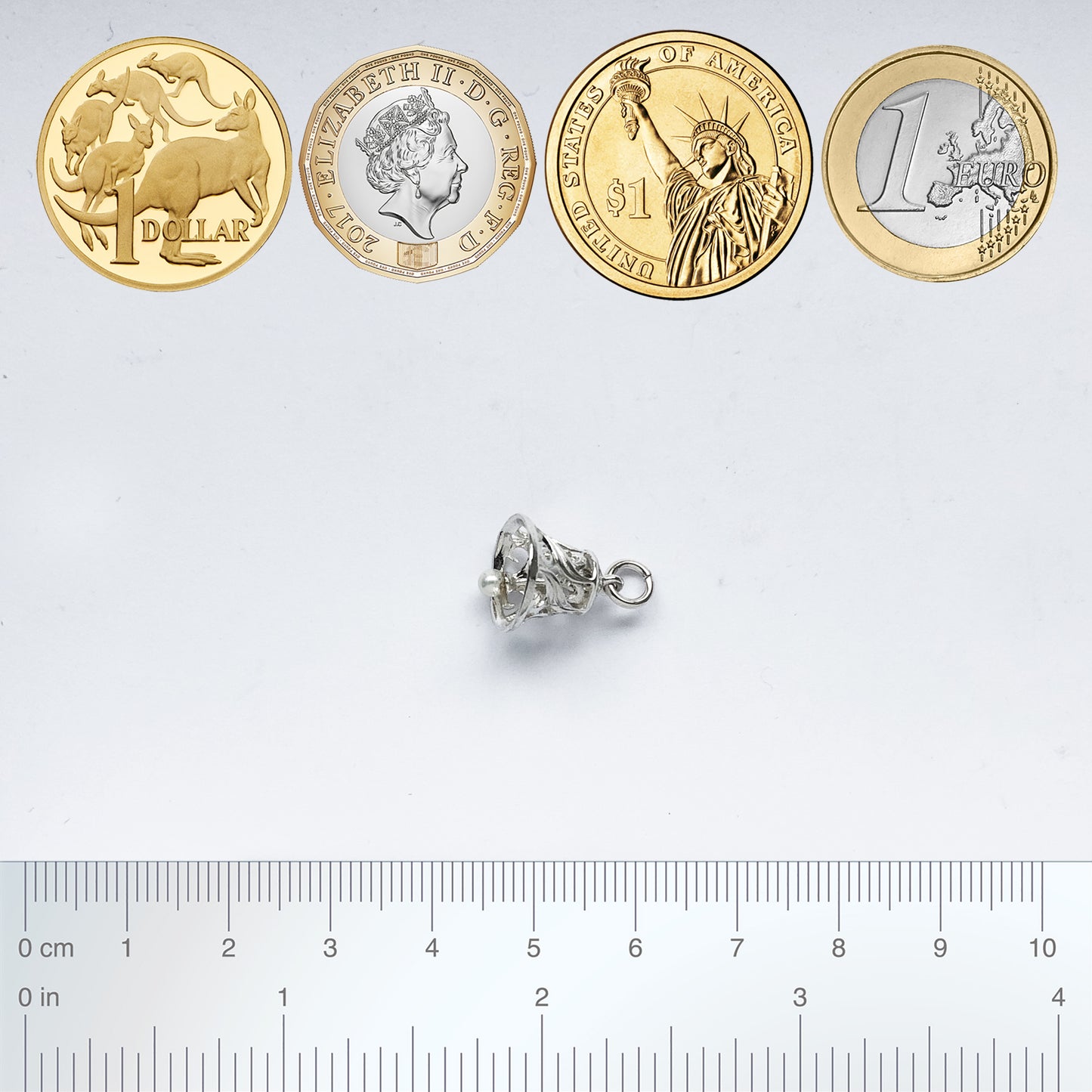 bell charm with coins and ruler for scale