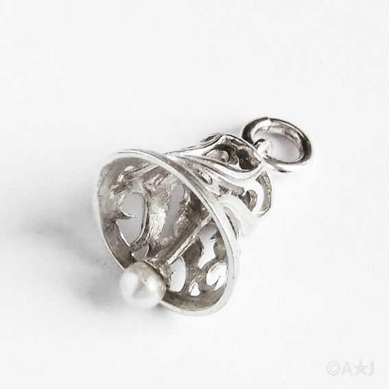 Silver bell pendant with pearl clapper on a grey background