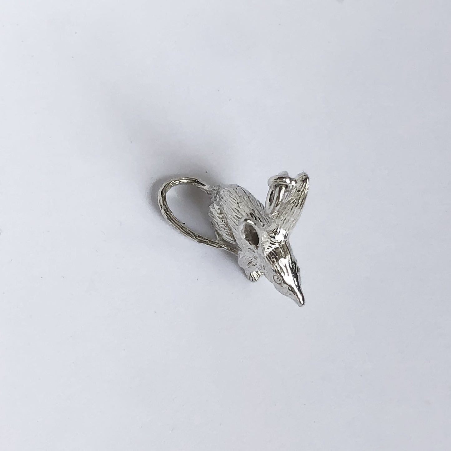 silver bilby charm seen from above, on a light grey background