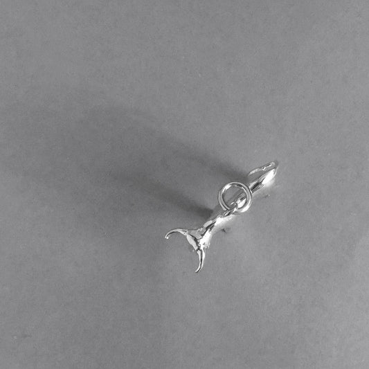 Sterling silver bull charm from above on a grey background