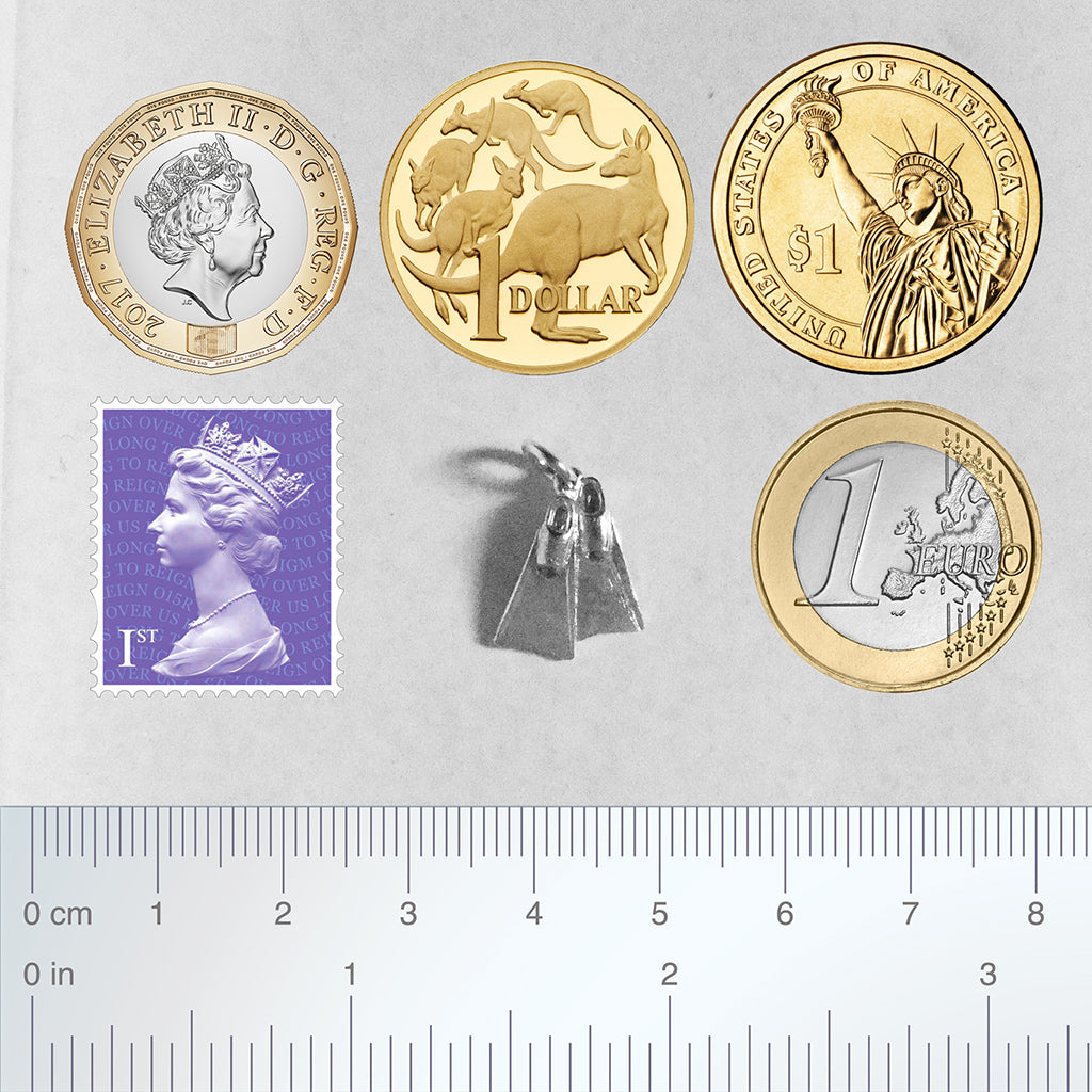 Sterling silver diving fins charm with coins, ruler and postage stamp for scale on a grey background