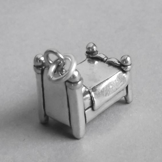 back side view of silver bed charm on grey background