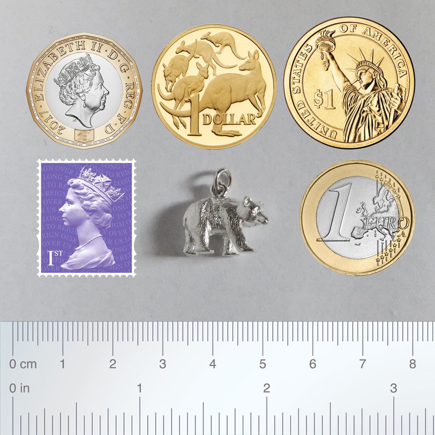 bear charm with coins ruler and postage stamp for scale