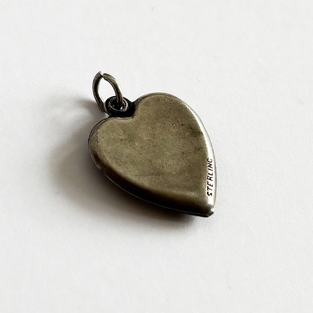 back of heart-shaped silver charm on a white background