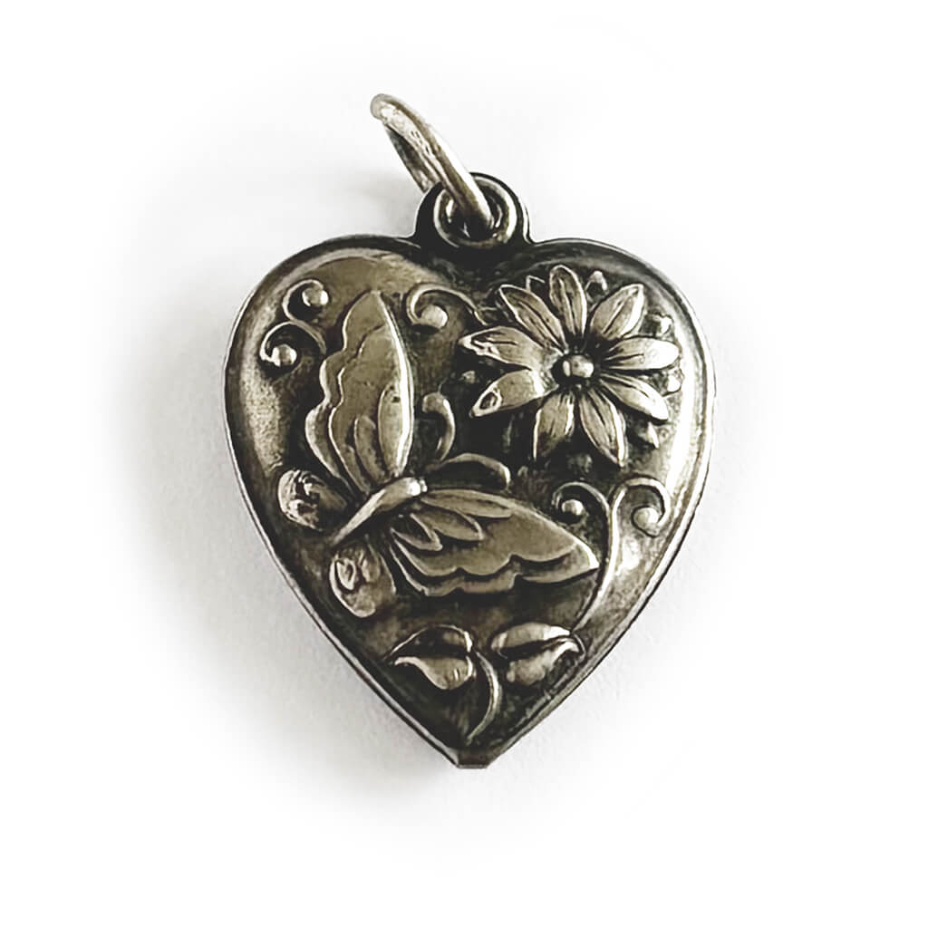Heart-shaped pendant with butterfly and floral design on a white background